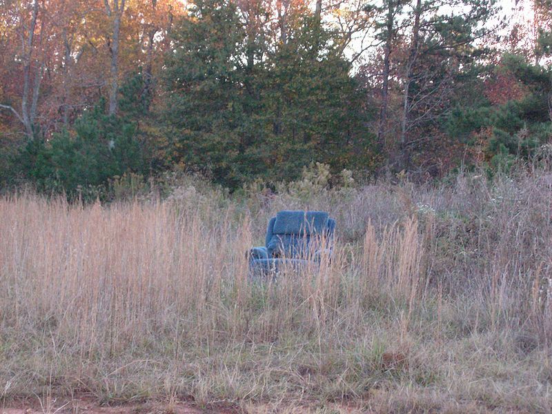 A dumped seat illegally littered on private property.